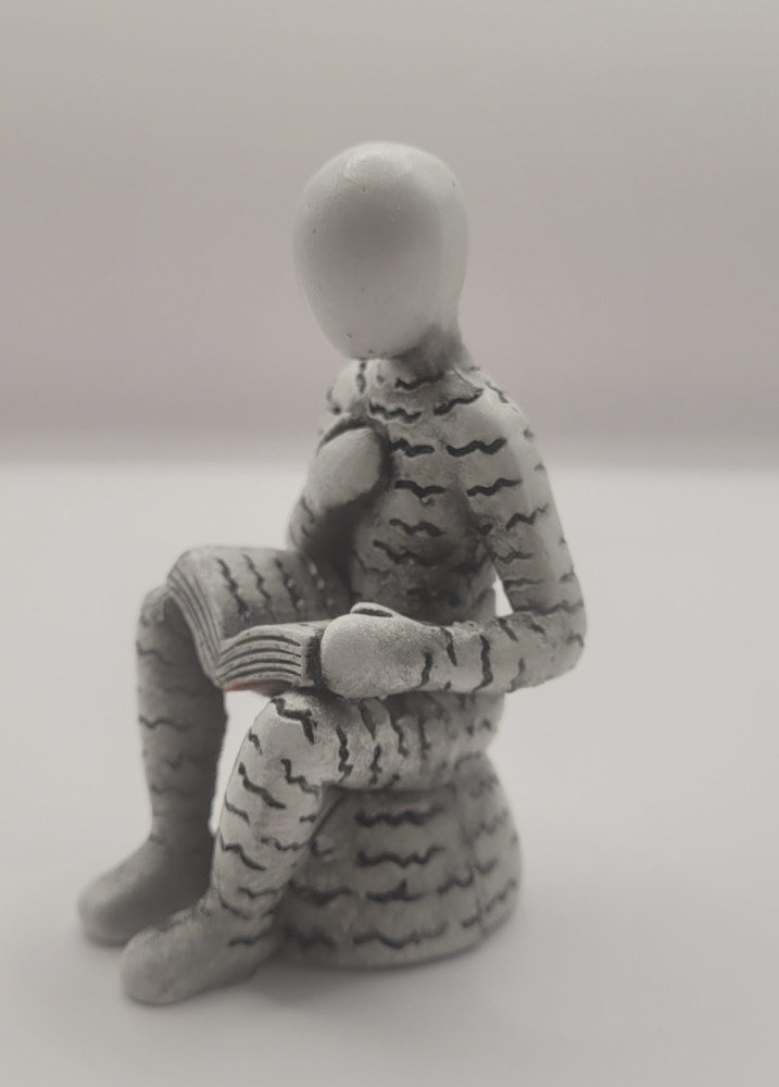 Bogro-figur siddende med hånden på brystet