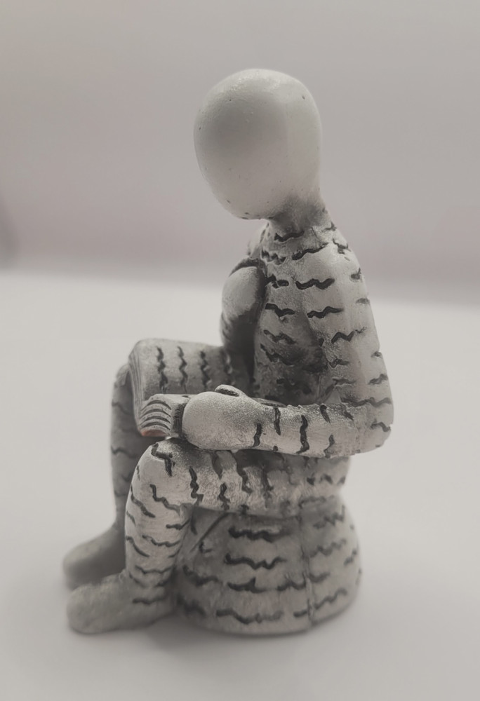 Bogro-figur siddende med hånden på brystet