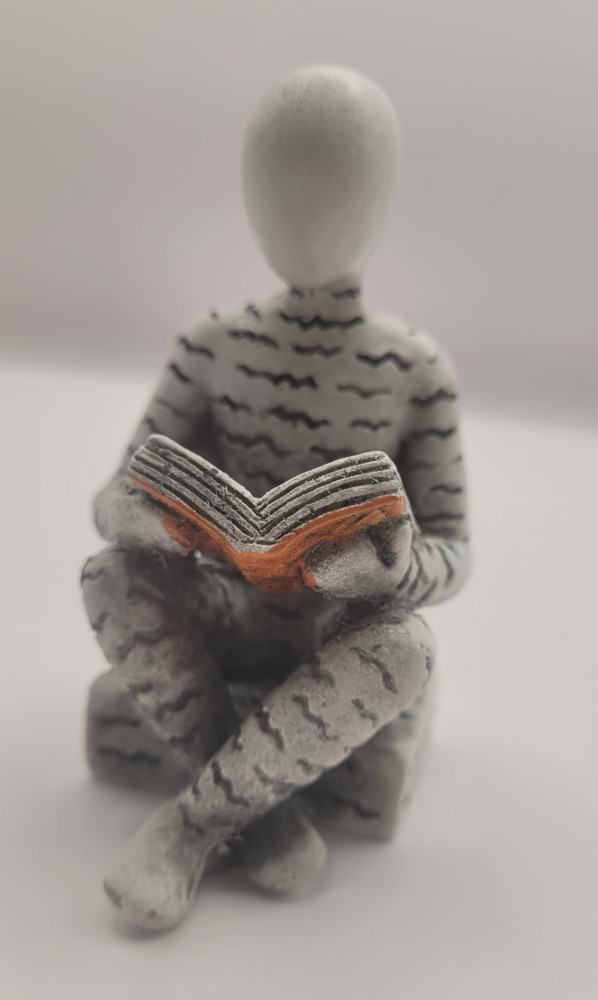 Bogro-figur siddende og læse