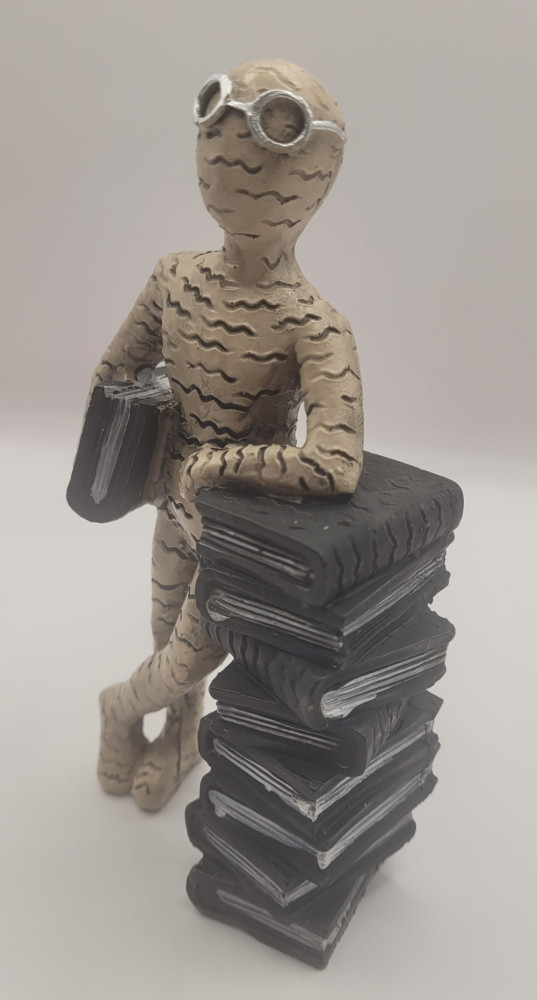 Bogro-figur stående ved bogstak. Brun