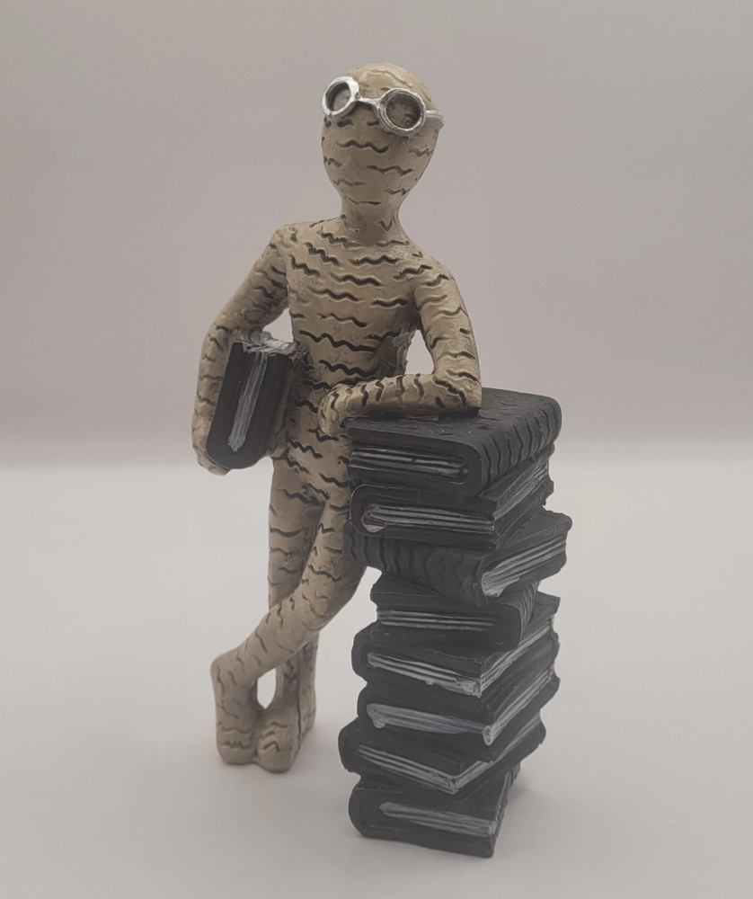 Bogro-figur stående ved bogstak. Brun